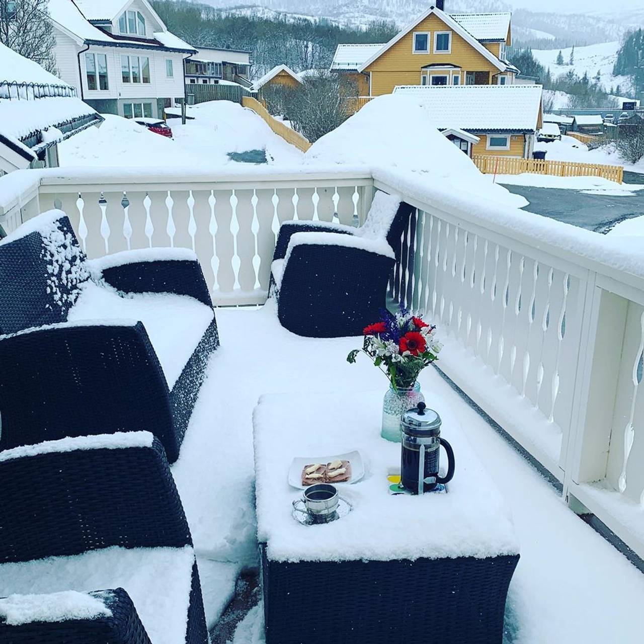 Her er det rigget til frokost på verandaen. Men hagemøblene er dekket i snø.