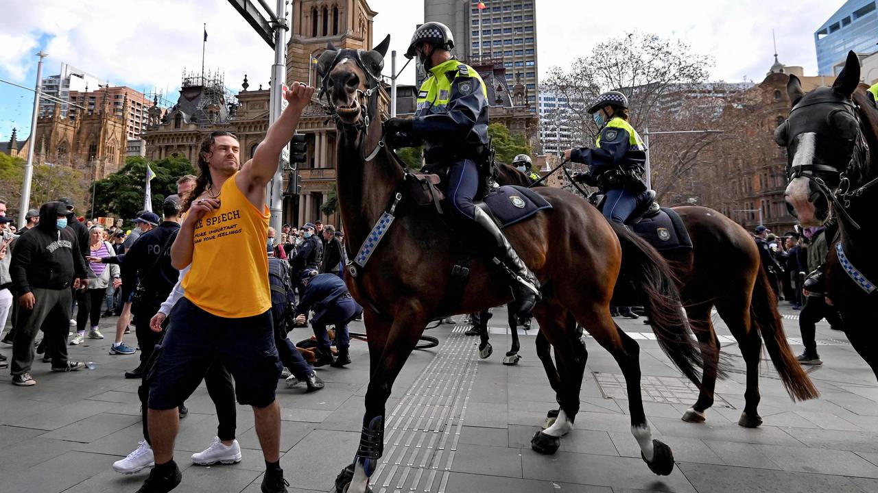 A protester (L) tries to push away a police horse in Sydney on July 24, 2021, as thousands of people gathered to demonstrate against the city's month-long stay-at-home orders.