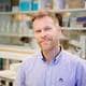 NMBU/Alexander Benjaminsen En mann i skjorte som ser direkte inn i kameraet. Han står inne i et laboratorium.