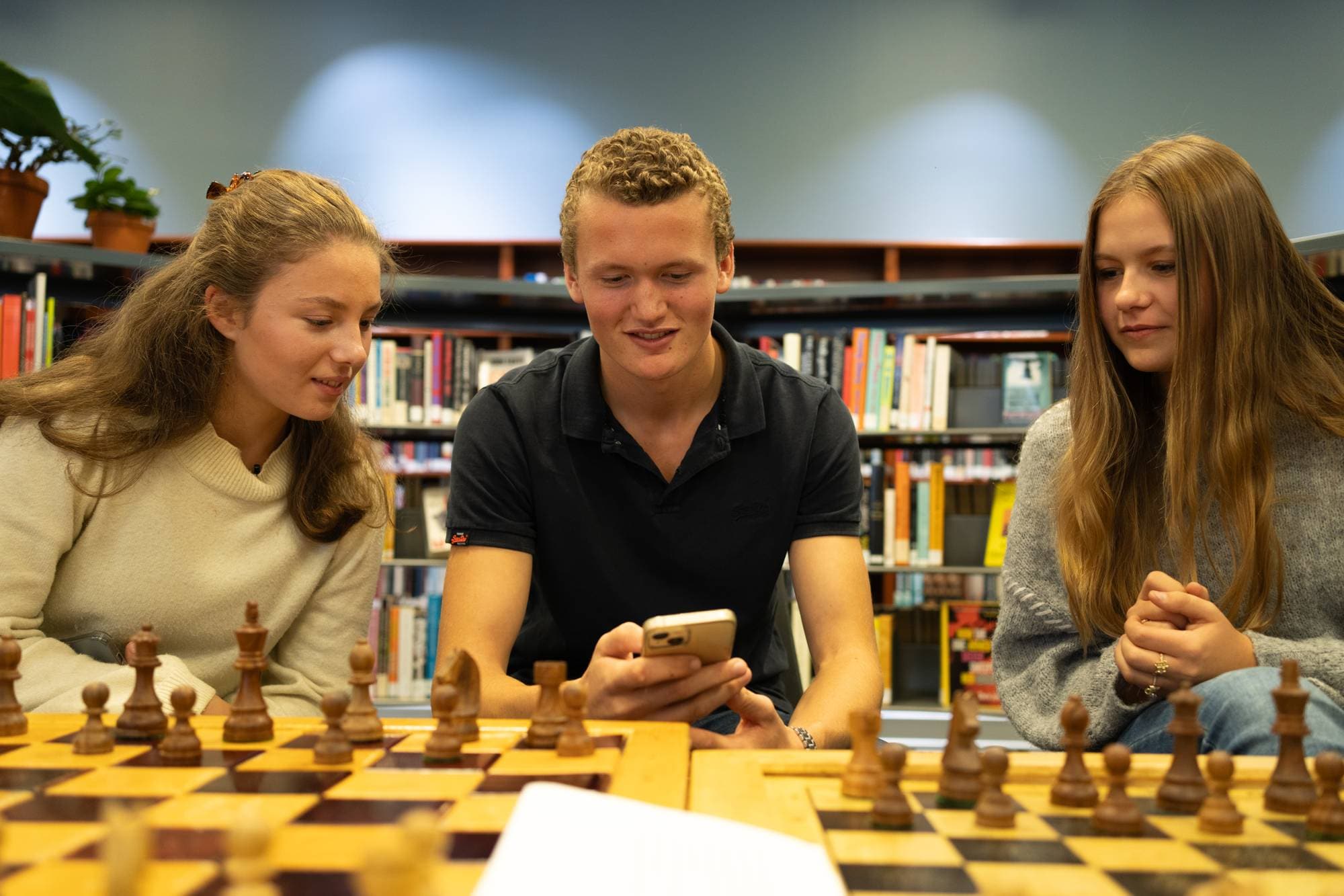 Martinius Foss Claussen viser fram reels fra Instagram ved et sjakkbrett på et bibliotek