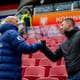 Fredrik Varfjell / NTB To menn gir hverandre hånden på en tribun. De står på en tribune med røde seter. Bak dem er det et banner med teksten "Koninklijke". (Bildebeskrivelsen er laget av en KI-tjeneste)