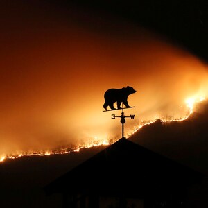 A weathervane sits on top of a barn over a wildfire near Dillard, Ga., Monday, Nov. 21, 2016. (Curtis Compton /Atlanta Journal-Constitution via AP)