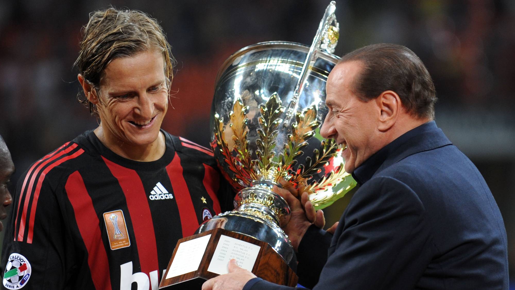 Silvio Berlusconi overrekker pokal til Milan-spiller Marek Jankulovski. (Bildebeskrivelsen er laget av en KI-tjeneste)