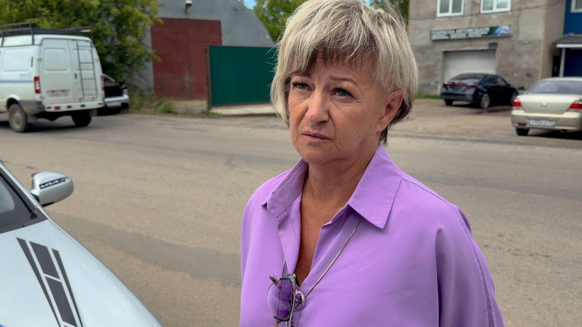 Kvinne i lilla skjorte ved bil i Russland.