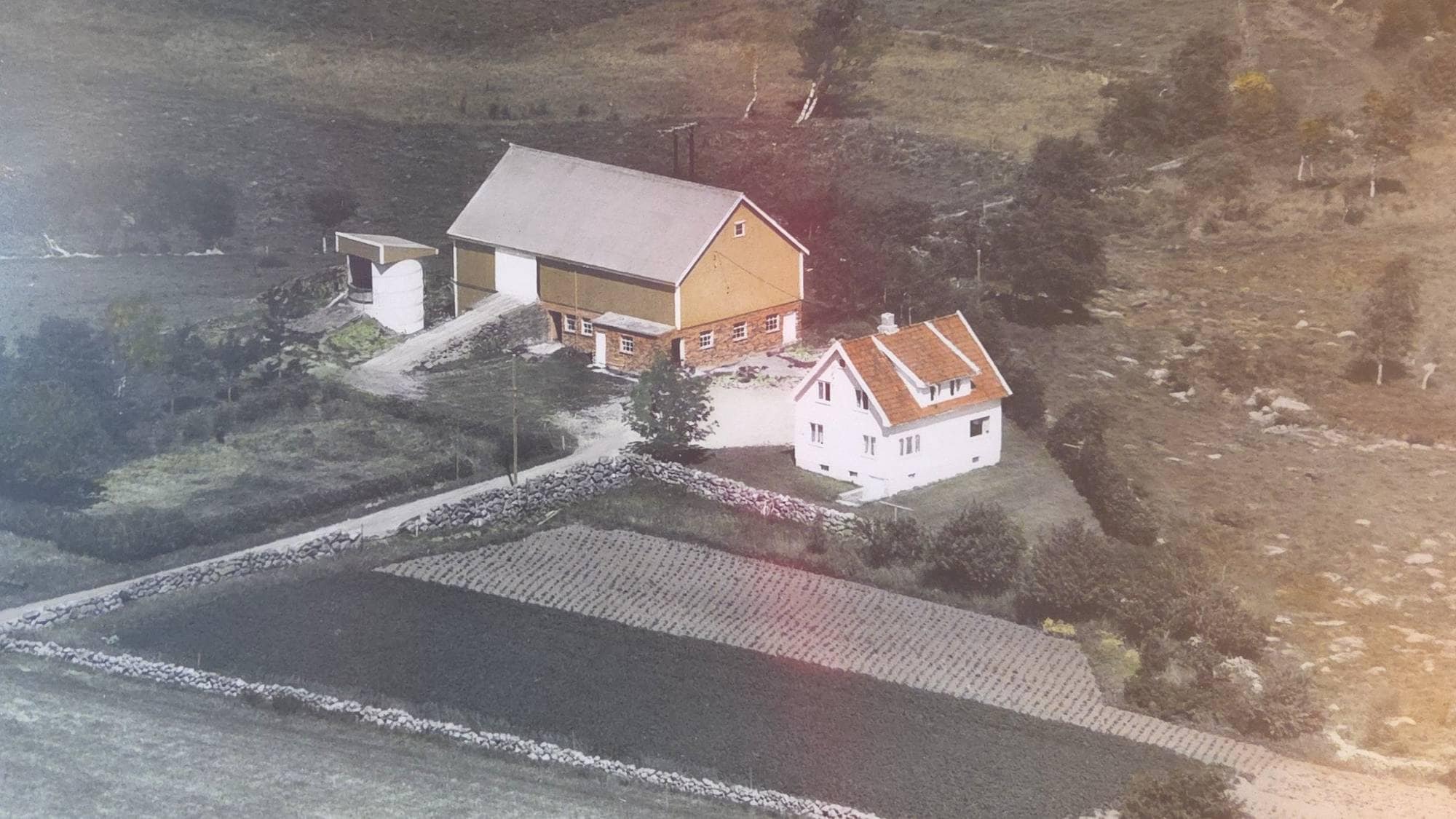 Gammelt foto av gårdstun på Jåttå i Stavanger. En gul driftsbygning og et hvitt hus