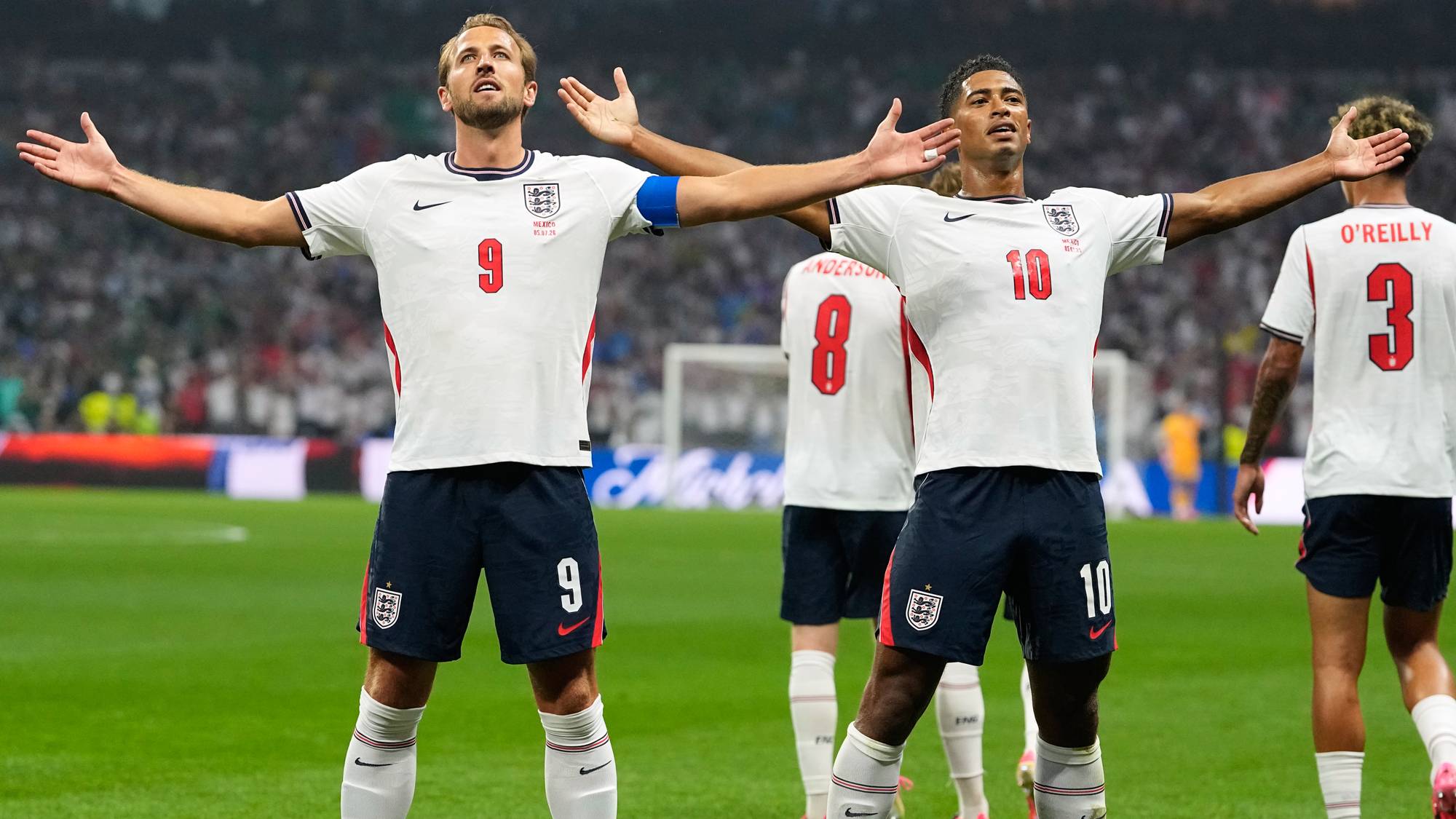 Harry Kane og Jude Bellingham feirer med utstrakte armer på en fotballbane. (Bildebeskrivelsen er laget av en KI-tjeneste)
