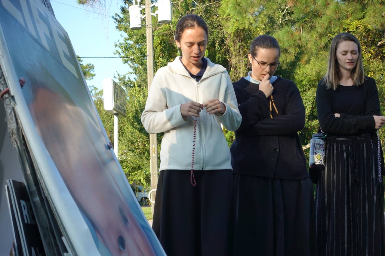 BER FOR FORBUD: Nancy McAndrew (22) (t.v), Hayden (18) og Lexi (18) samles til bønn foran abortklinikken. De går alle på katolsk skole i Florida. 
