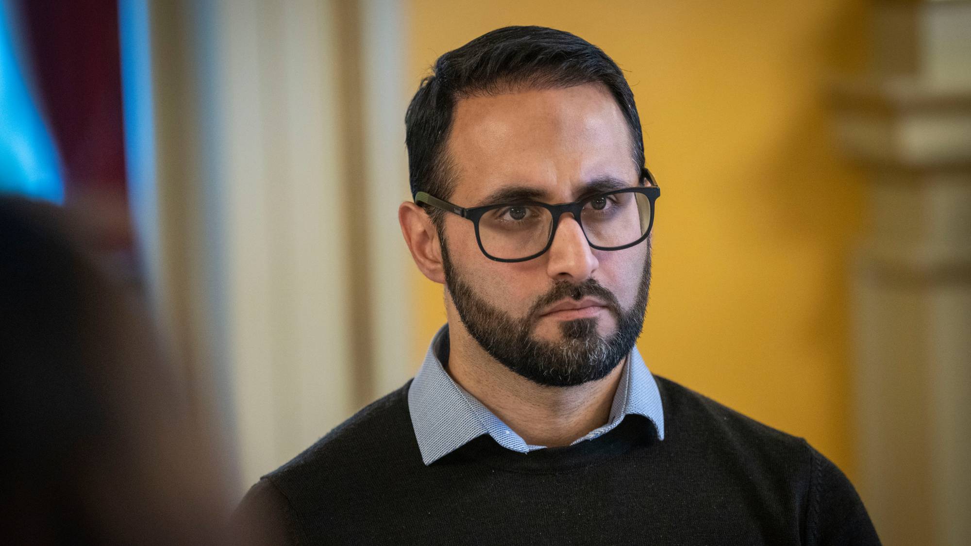 Mann med velstelt, kort skjegg, iført briller, lyseblå skjorte og mørk genser. (Bildebeskrivelsen er laget av en KI-tjeneste)