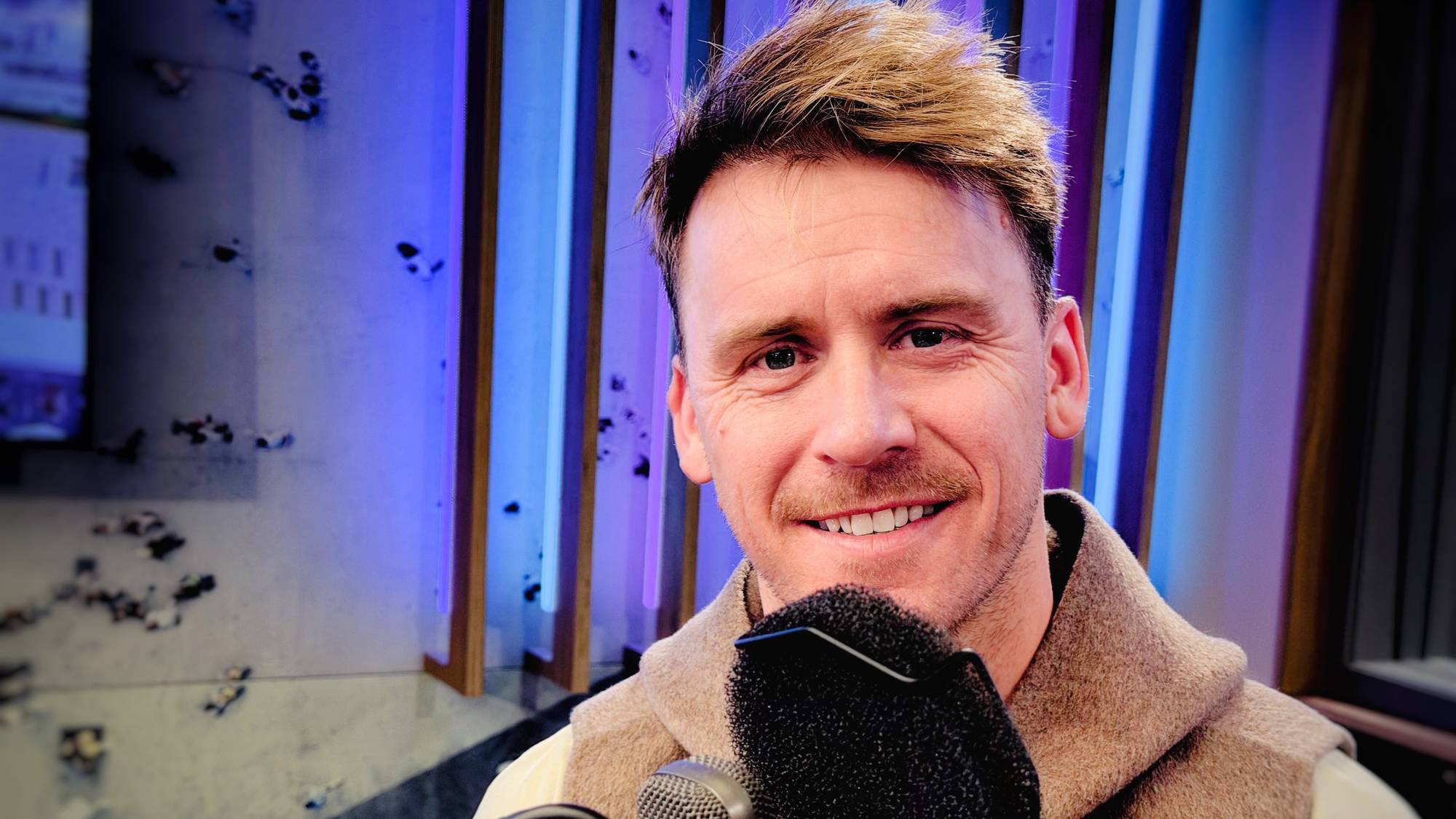 NRKs fotballekspert Carl-Erik Torp i radiostudio - sutter ved mikrofonen. Halvnært snitt