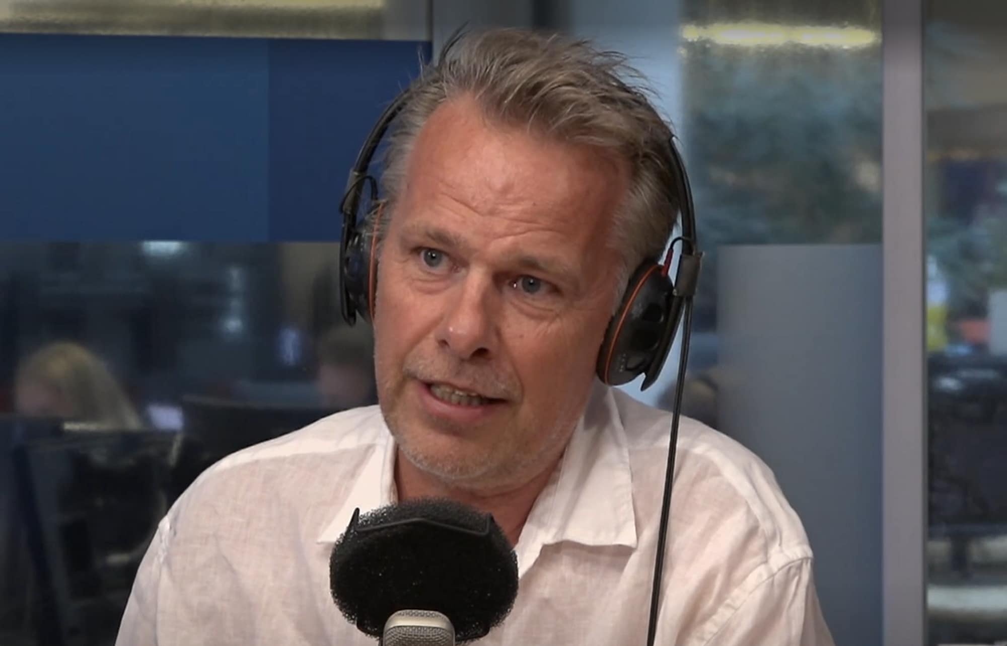 Mann med hodetelefoner snakker inn i en mikrofon i et studio. (Bildebeskrivelsen er laget av en KI-tjeneste)