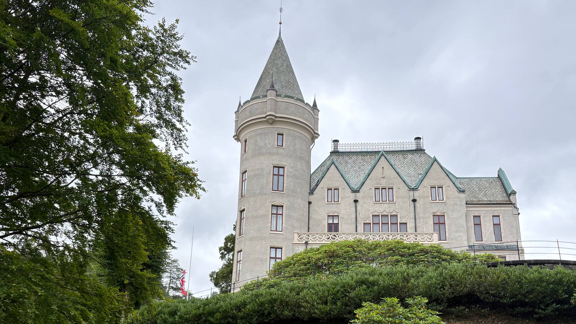Gamlehaugen i Bergen, blant grønt gress. Flagget vaier på halv stang etter kong Haralds død.