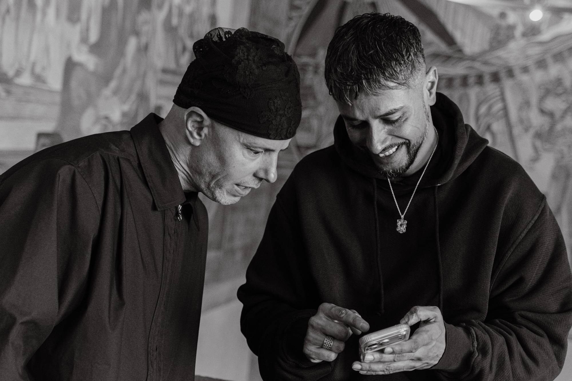 Chirag viser noe på mobilen til Magdi som ser overrasket ut