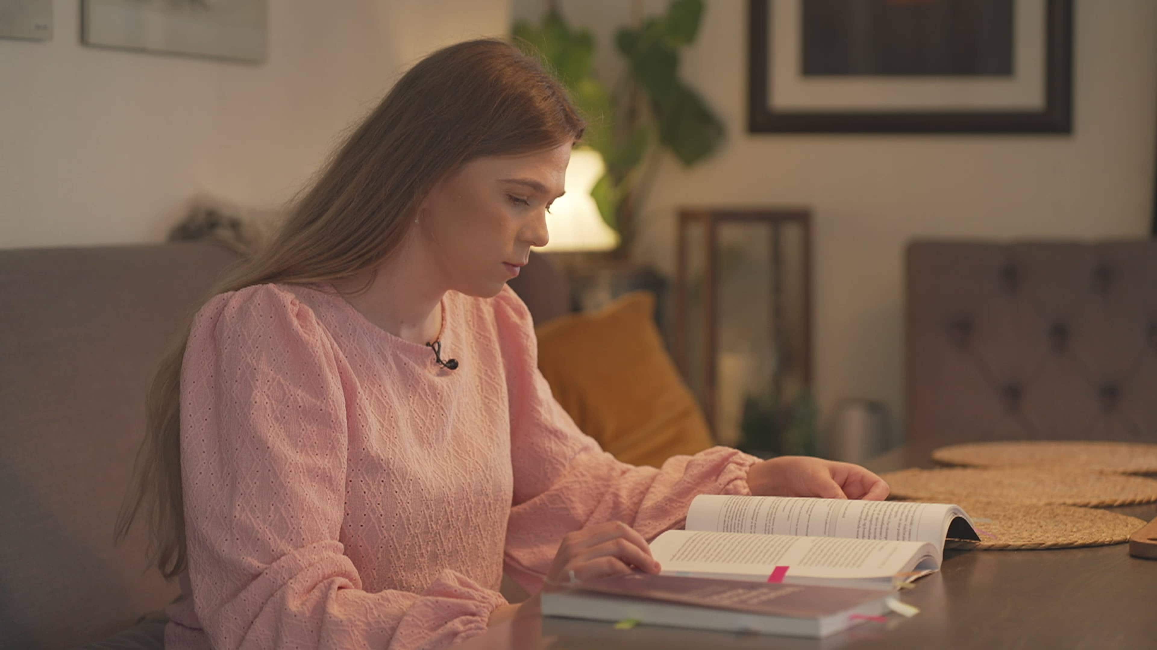Elise sitter med bok i sofaen.