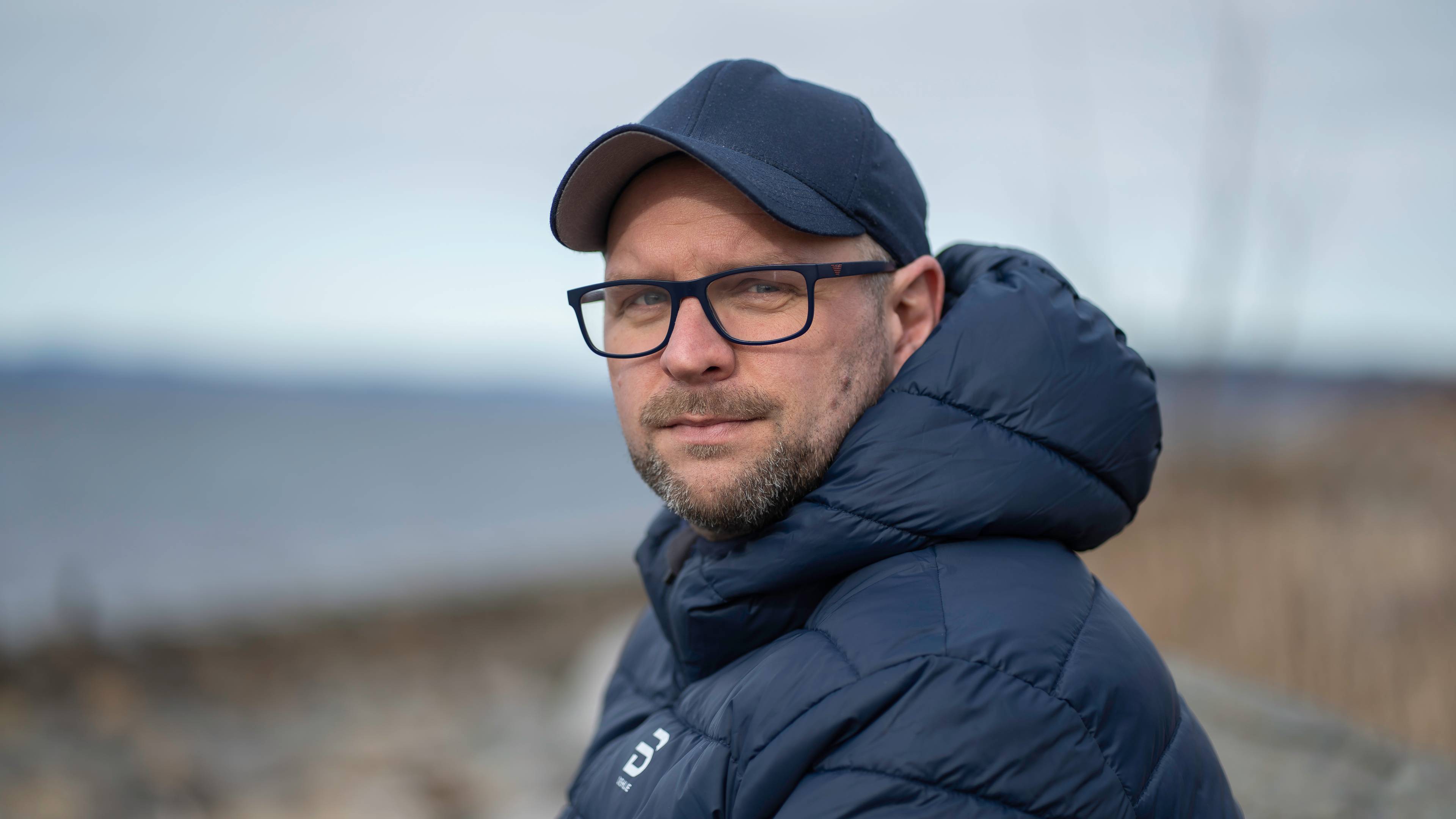 Mann med kaps og jakke ser mot kamera