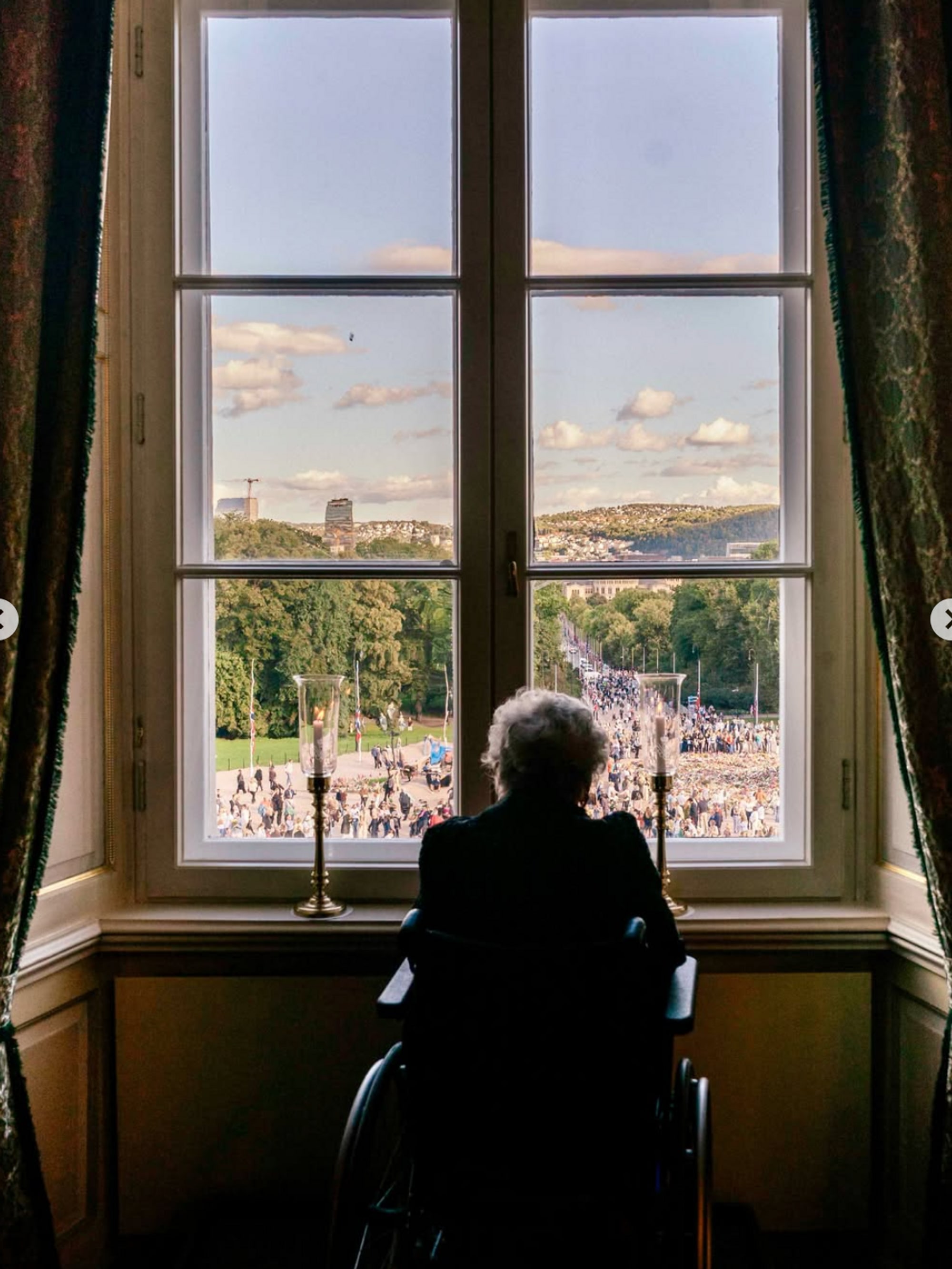 Prinsesse Astrid kikker ut av vinduet på Slottet. Hun ser ut på folkemengden.