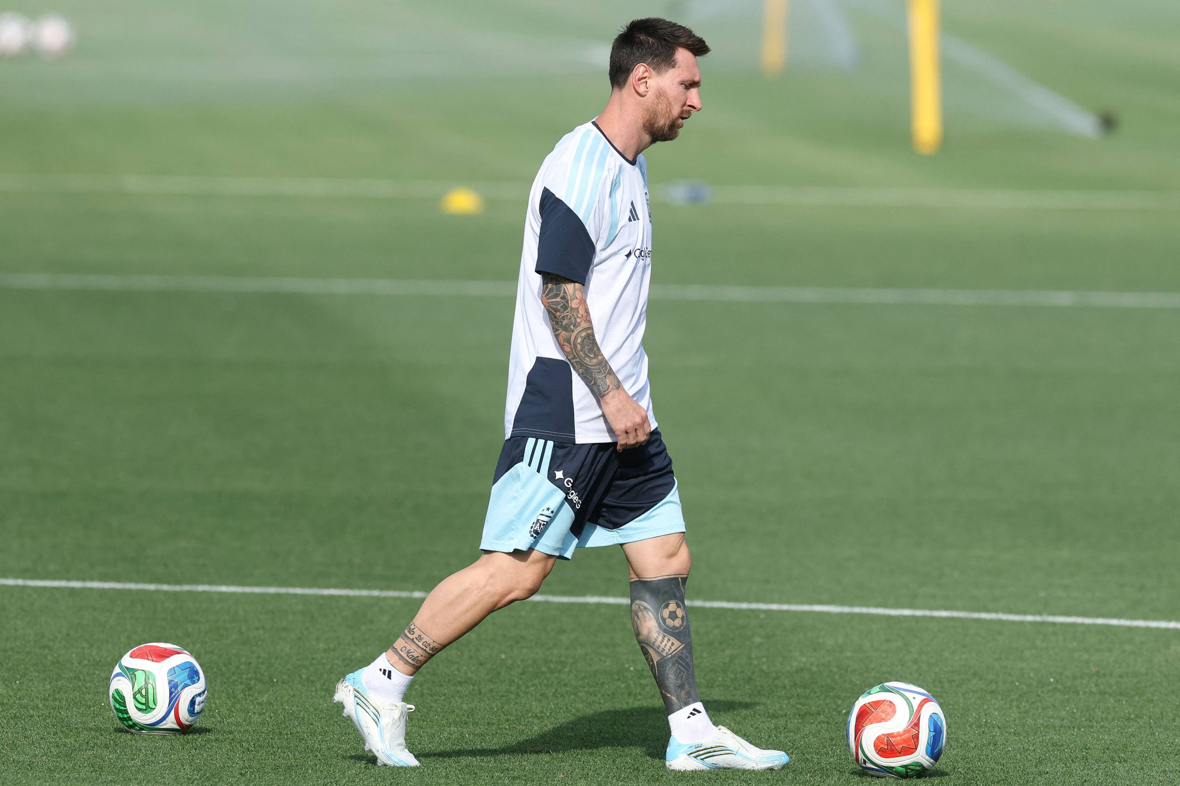 Fotballspiller Lionel Messi trener på en kunstgressbane. Han er ikledd Argentinas drakter. To fotballer ligger på gresset. (Bildebeskrivelsen er laget av en KI-tjeneste)
