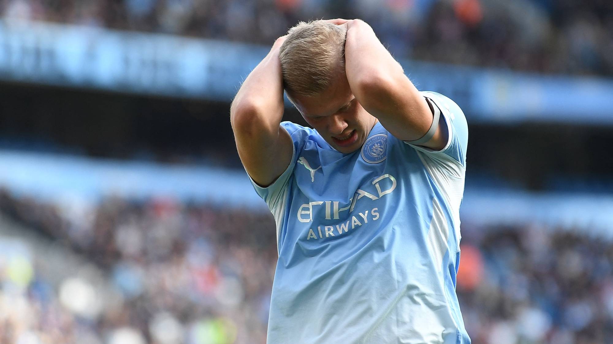 Erling Braut Haaland i Manchester City-drakt holder seg til hodet på en fotballstadion. (Bildebeskrivelsen er laget av en KI-tjeneste)