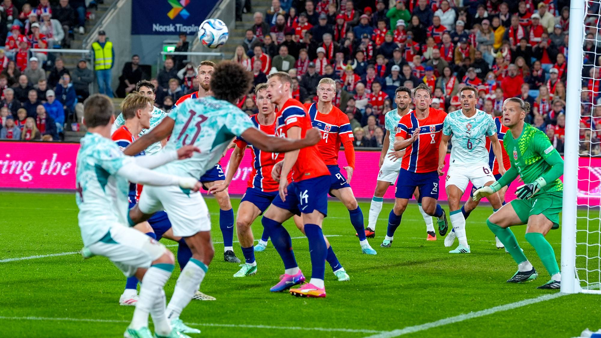 Fotballspillere fra Norge og Portugal kjemper om ballen foran mål under en landskamp. (Bildebeskrivelsen er laget av en KI-tjeneste)