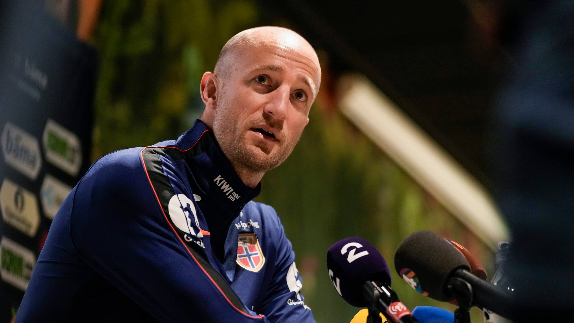 Brede Hangeland snakker i mikrofoner under en pressekonferanse. Han er kledd i landslagsdrakt. (Bildebeskrivelsen er laget av en KI-tjeneste)