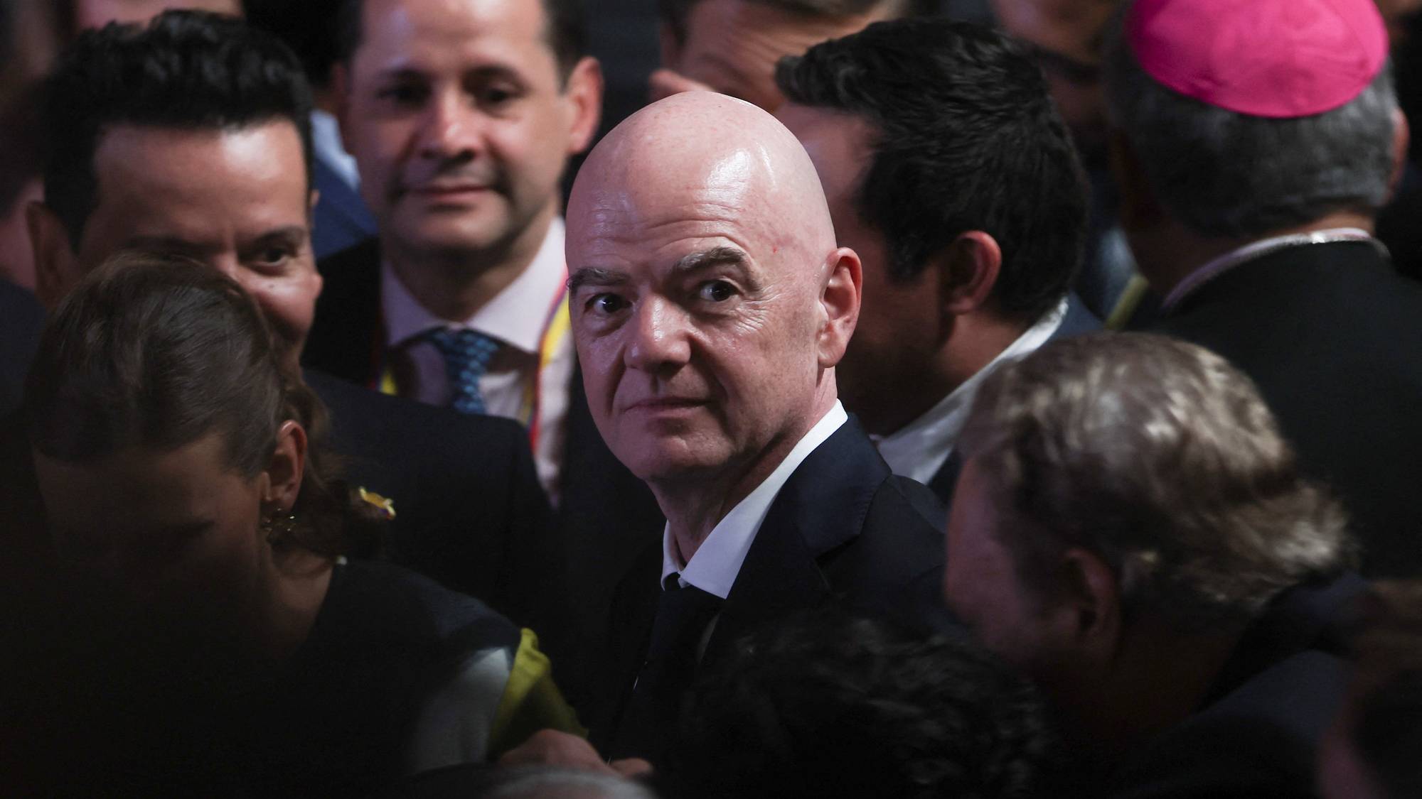 FIFA-president Gianni Infantino i en folkemengde omgitt av andre personer i dress. (Bildebeskrivelsen er laget av en KI-tjeneste)