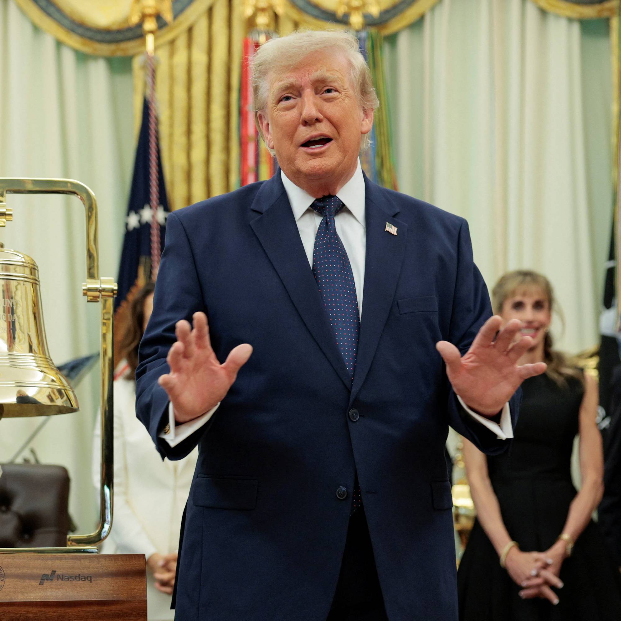 Donald Trump taler ved en børsbjelle i Det hvite hus, flankert av flere personer. (Bildebeskrivelsen er laget av en KI-tjeneste)