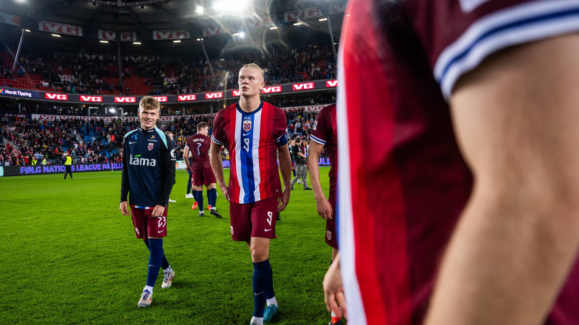 Erling Braut Haaland og andre norske landslagsspillere går over gressmatten på Ullevaal stadion. (Bildebeskrivelsen er laget av en KI-tjeneste)