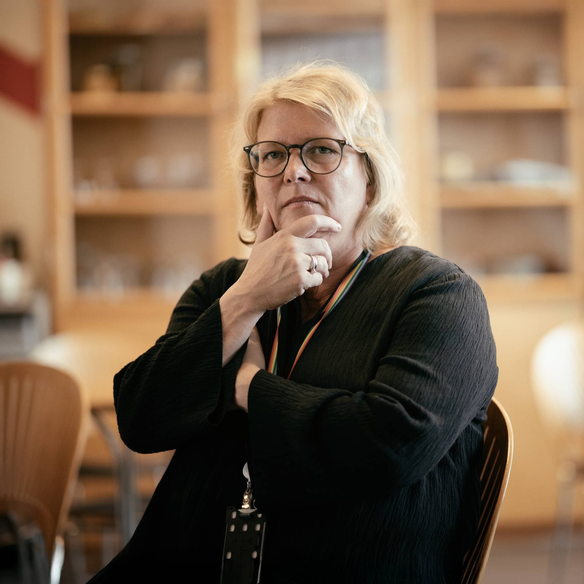 En dame med sorte klær og blondt hår ser inn i kamera.