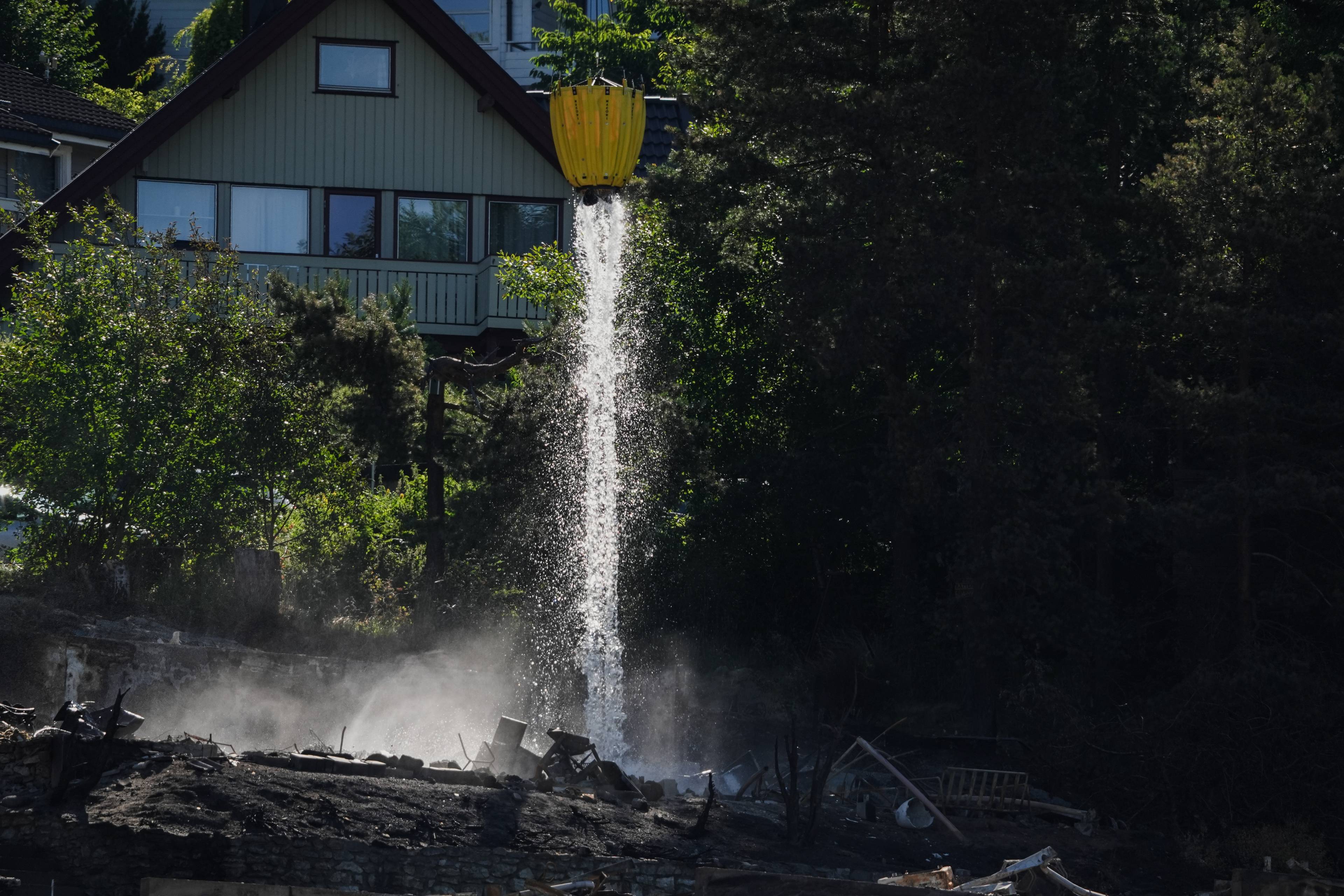 Vann droppes fra et helikopter over brente ruiner