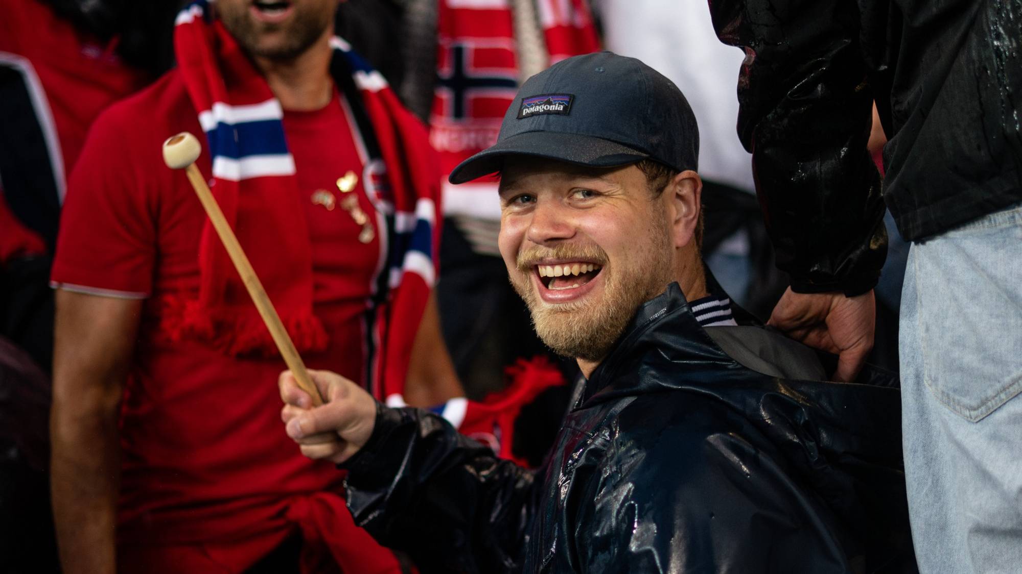 En mann slår på en stortromme og smiler mot kamera.