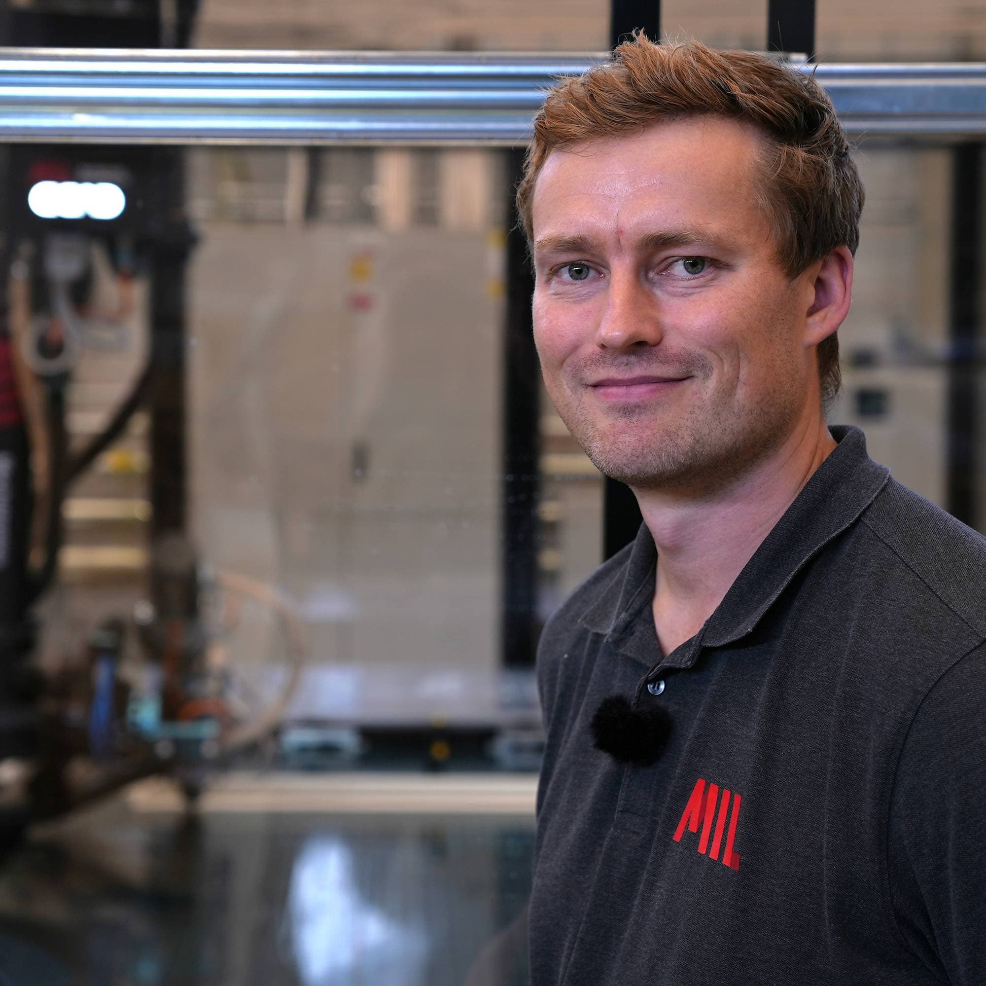 Mann med svart genser med 3D printer i bakgrunnen