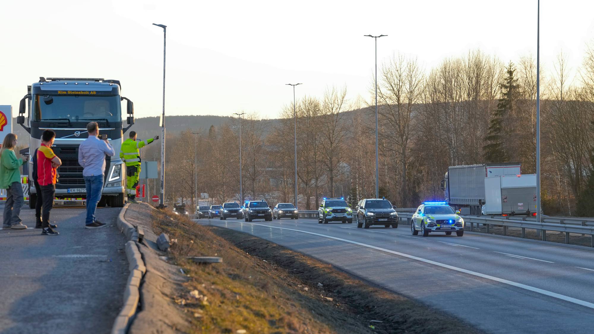 Politi og trafikkdirigent ved en stanset lastebil på en vei med utrykningskjøretøy. (Bildebeskrivelsen er laget av en KI-tjeneste)