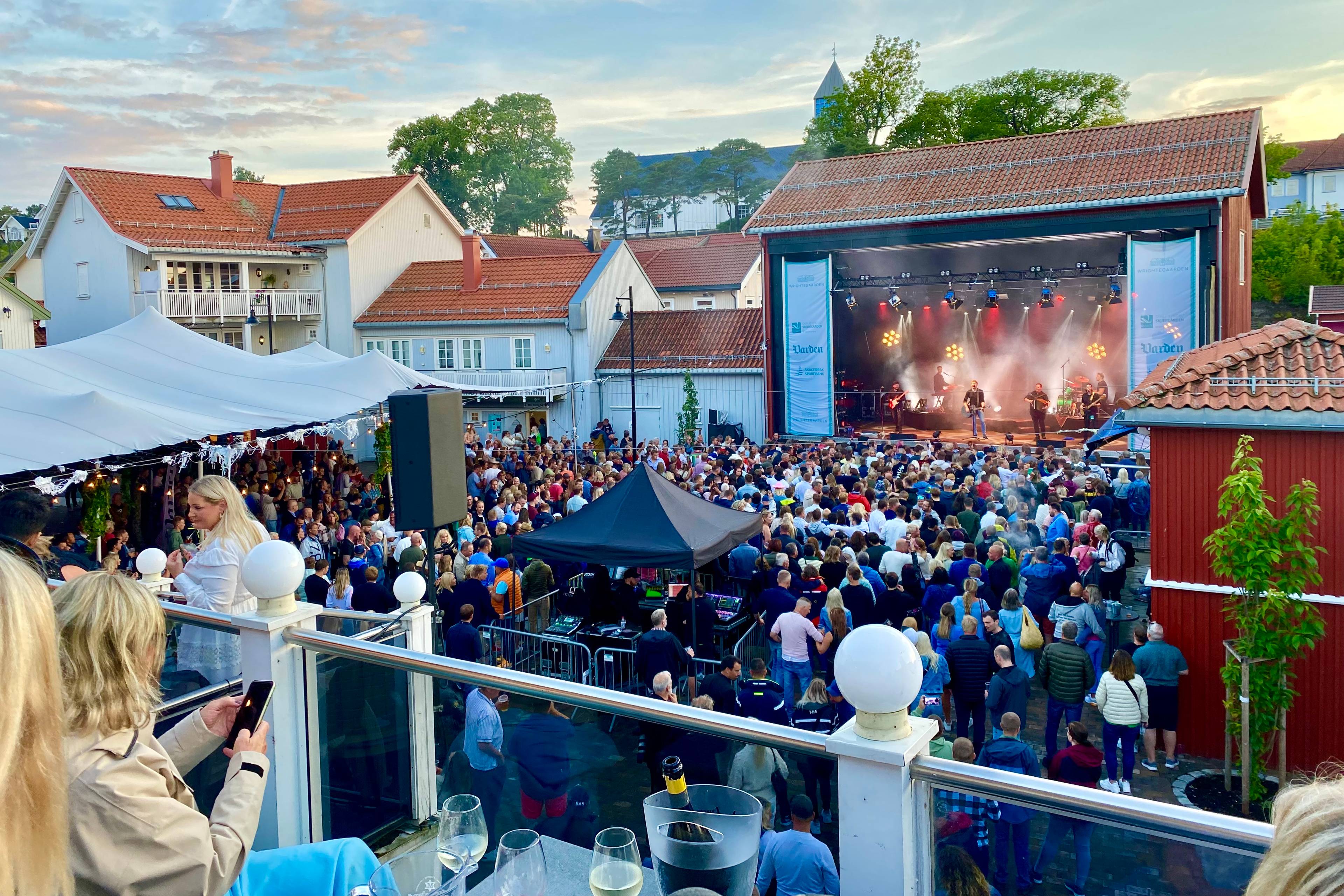 En gruppe mennesker som ser og hører på konsert midt på sommeren (Bildebeskrivelsen er laget av en KI-tjeneste)