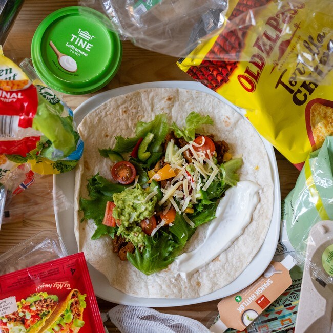 Bildet viser en tallerken med taco omringet av plastemballasjen fra ingrediensene brukt til å lage måltidet.