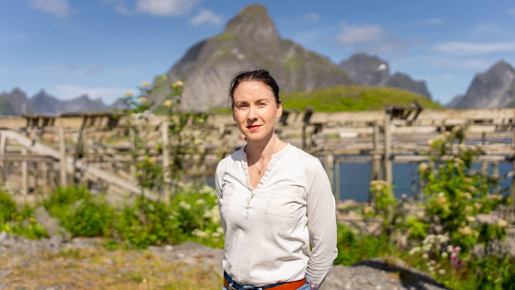 en person som står på en eng med et fjell i bakgrunnen