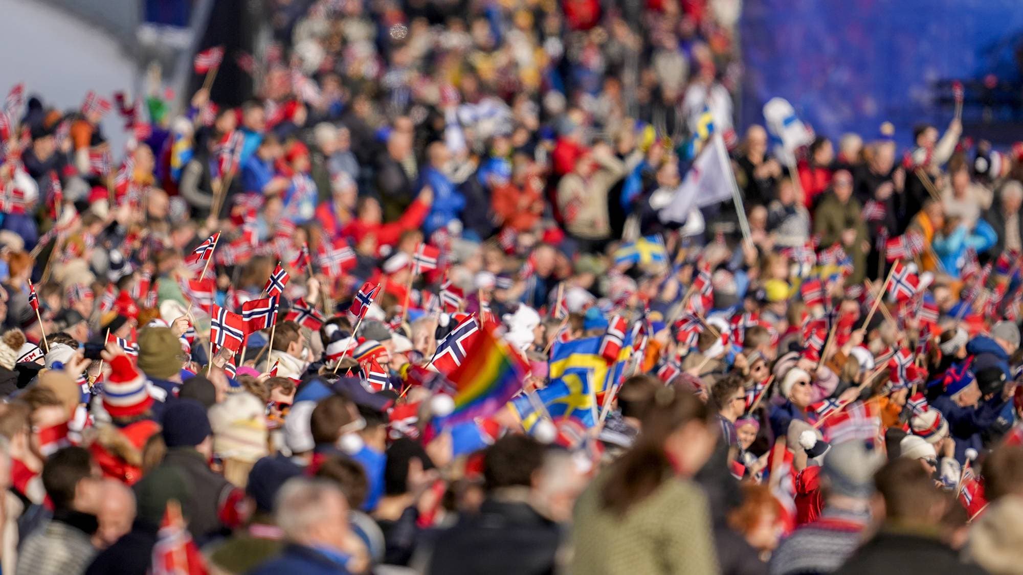 En folkemengde med mange norske flagg og enkelte svenske flagg på en skiarena. (Bildebeskrivelsen er laget av en KI-tjeneste)