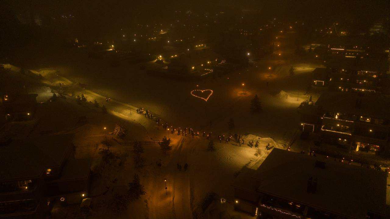 Dronebilde tatt over nabolag i nærheten av skredområdet i Gjerdrum. Mørklagt nabolag, lyshjerte i midten. Tente lys ved hvert hus.