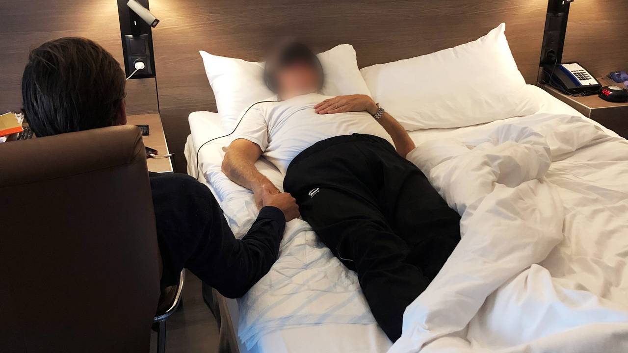 Håkon sitter ved siden av sengen der kunden ligger.