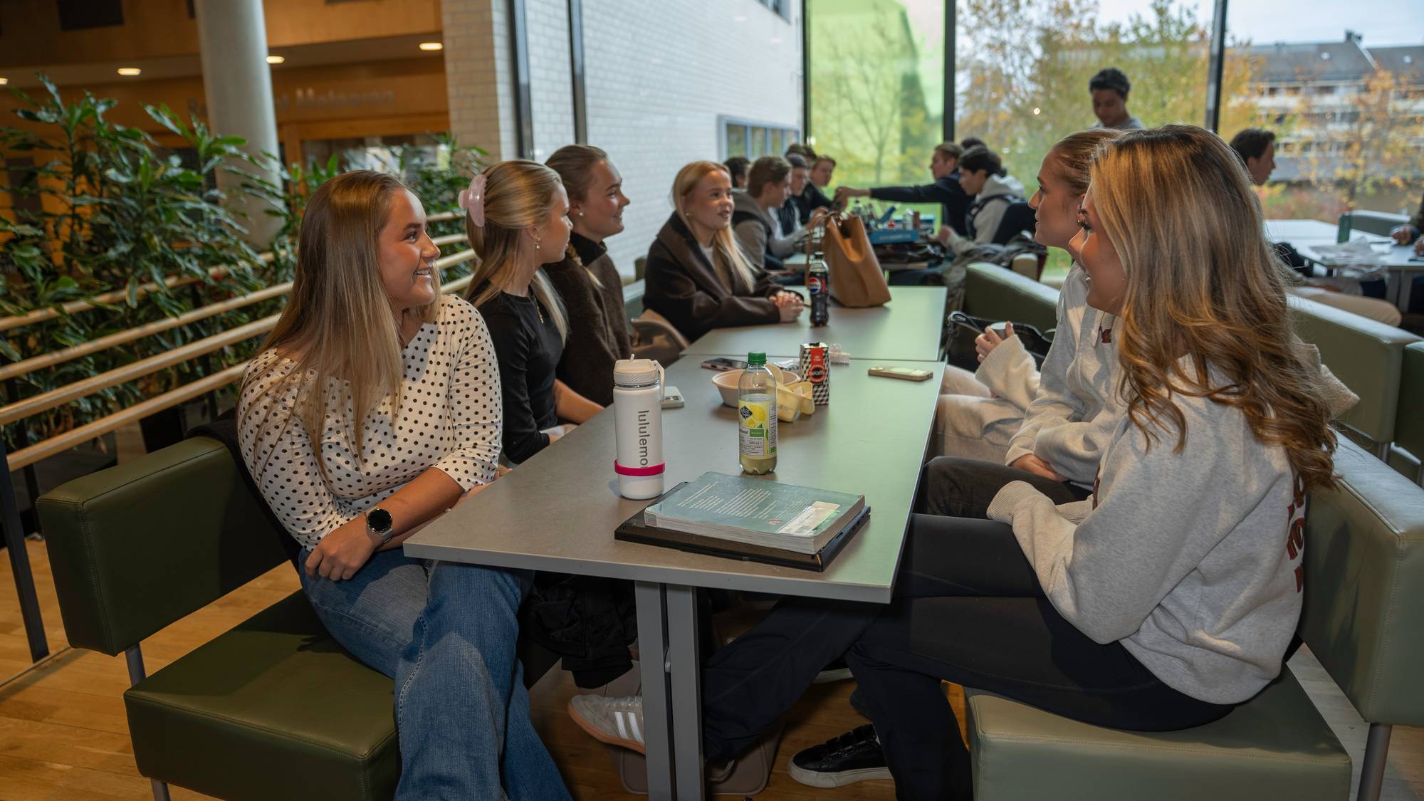 Elever på Byåsen videregående skole sitter ved et langbord i kantinen. I forgrunnen sitter Sofie Haltstrand.