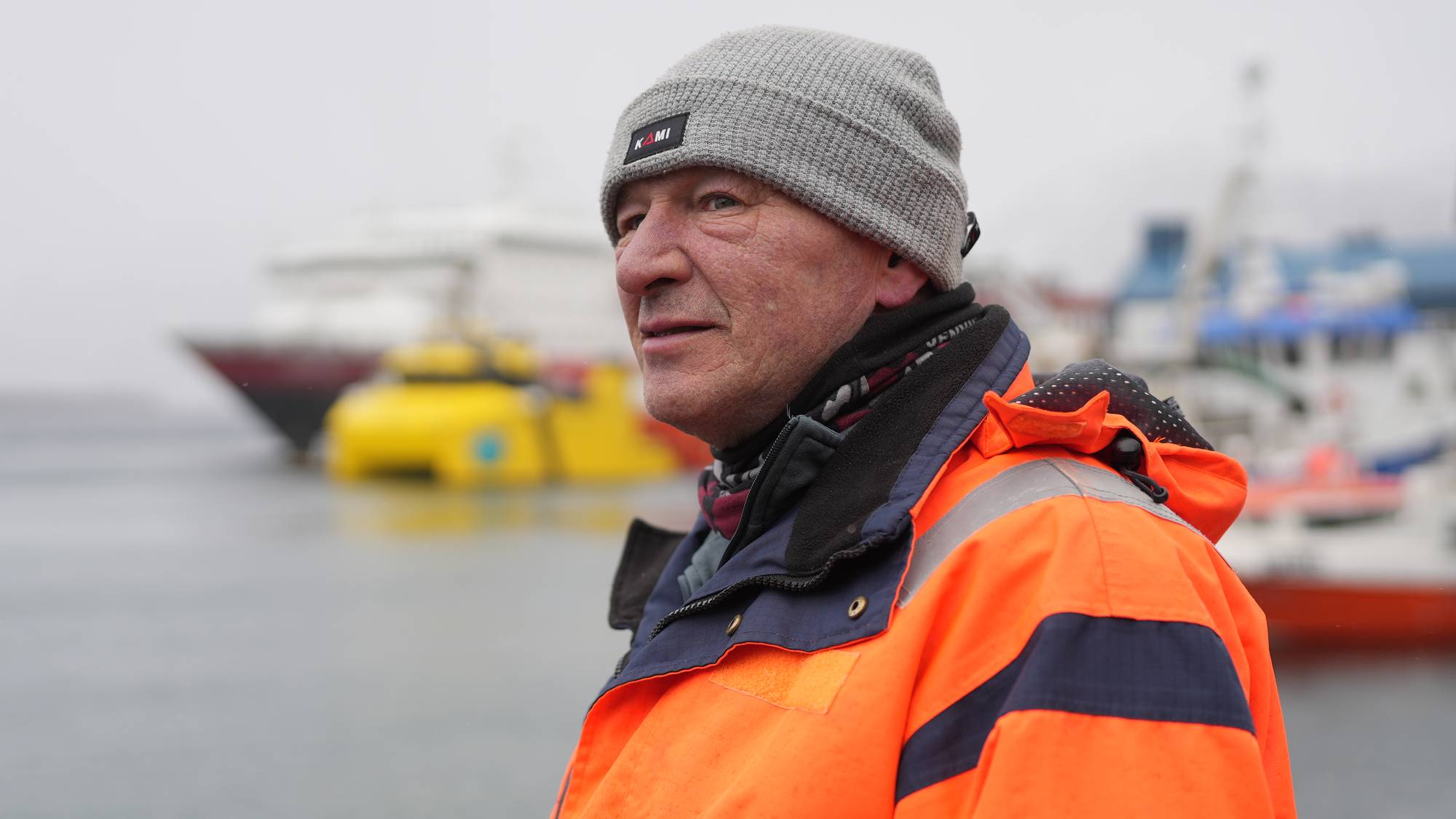 Arve Olsen i arbeidsklær på kaia Honningsvåg med hurtigruta Nordlys i bakgrunnen