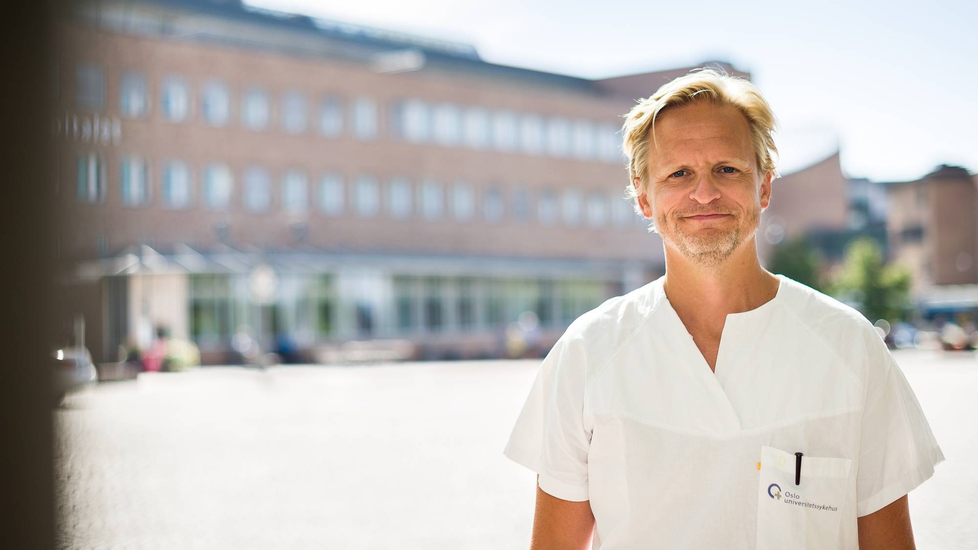 Johannes Hov står utendørs med hvit legedrakt på.