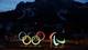 Claudia Greco / Reuters / NTB Olympiske og paralympiske emblem er synlige i mørket. Bakgrunn viser snødekte fjell og ishalling. Lysene fra bygningene gir en koselig atmosfære. Bildet illustrerer forberedelser til vinter-OL.