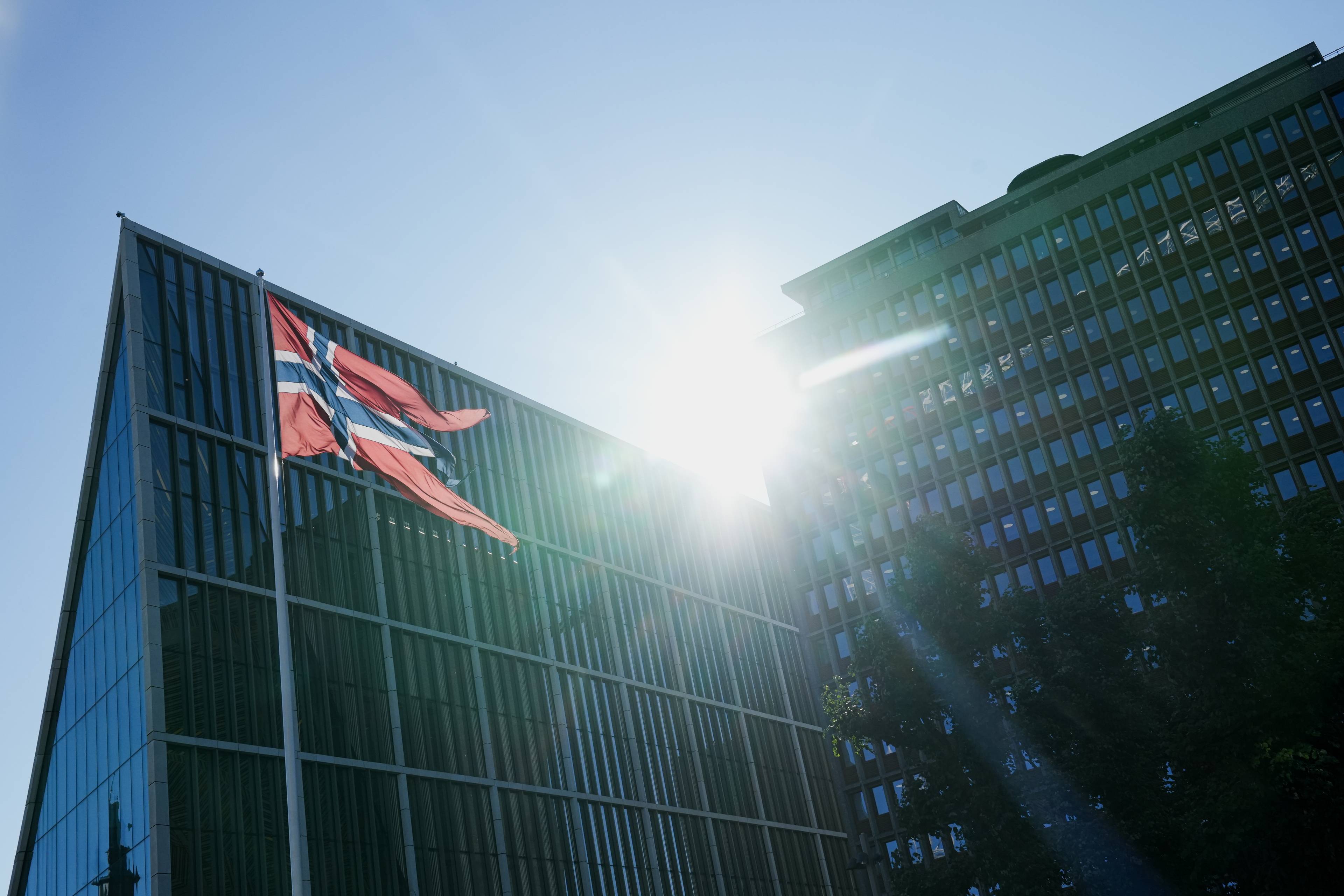 Et norsk flagg vaier i vinden foran Regjeringskvartalet