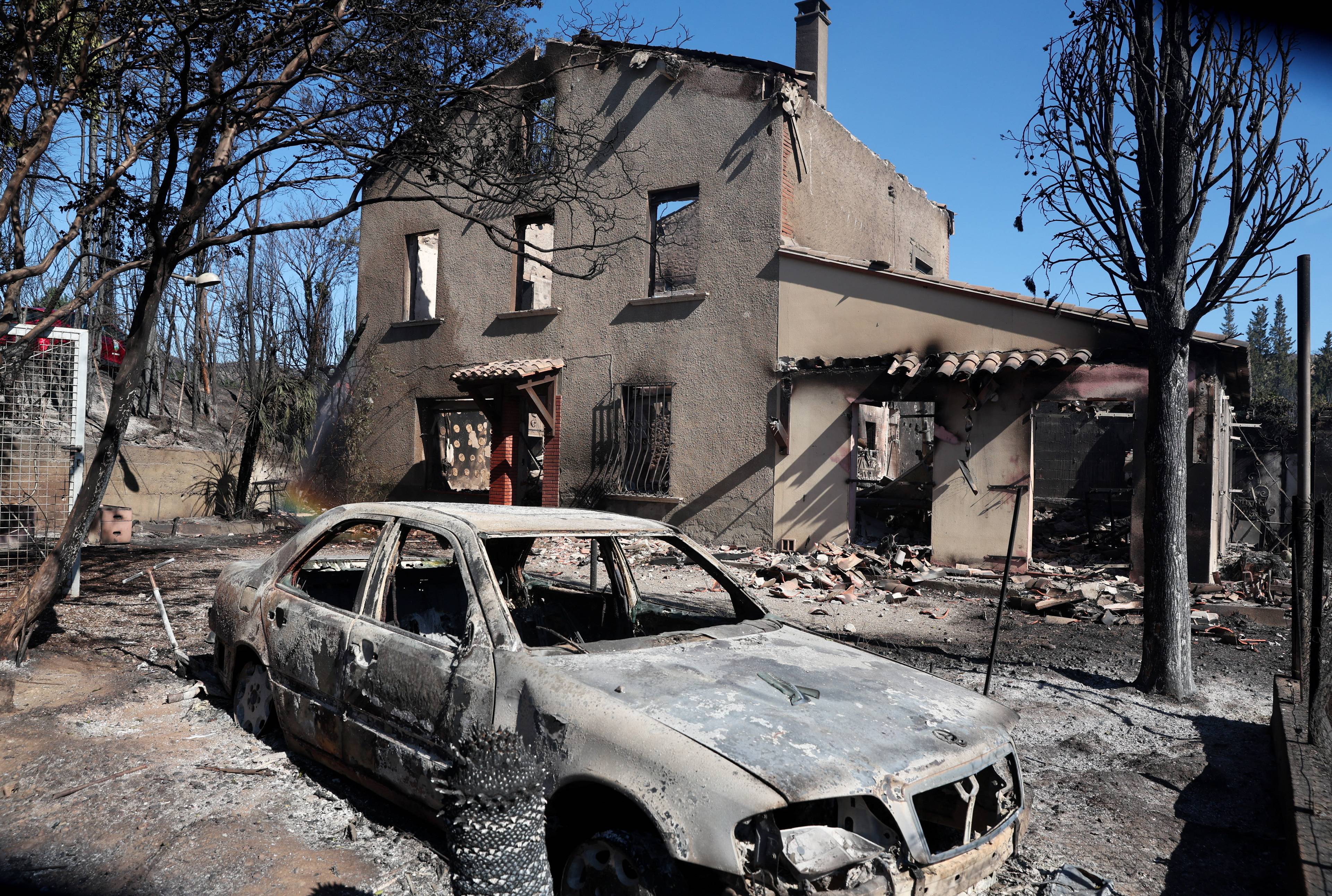 En utbrent bil foran et utrbent huss.