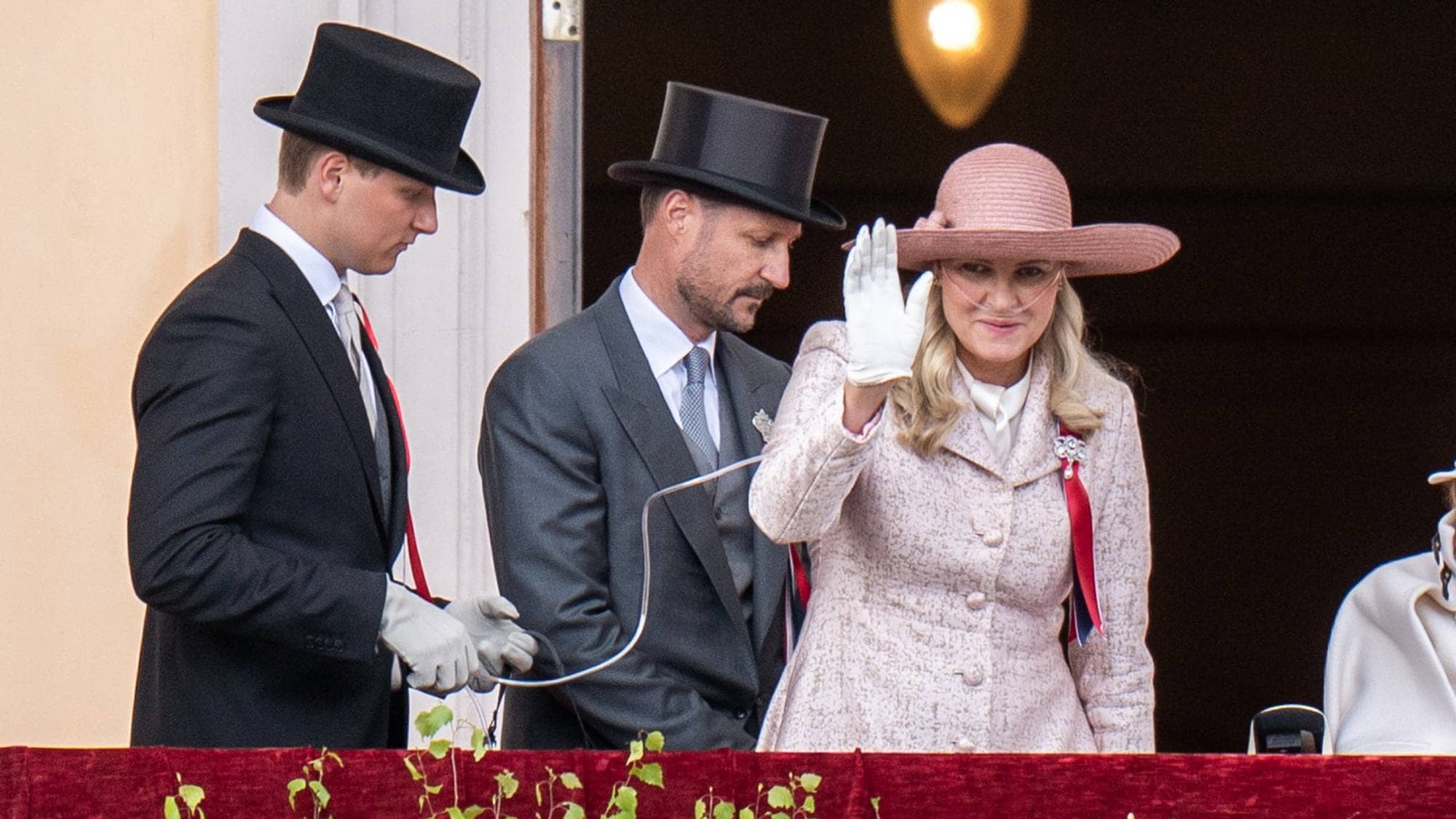 Prins Sverre Magnus holder pustemaskinen til kronprinsesse Mette-Marit mens de hilser på barnetoget i Oslo fra Slottsbalkongen på Slottet.
