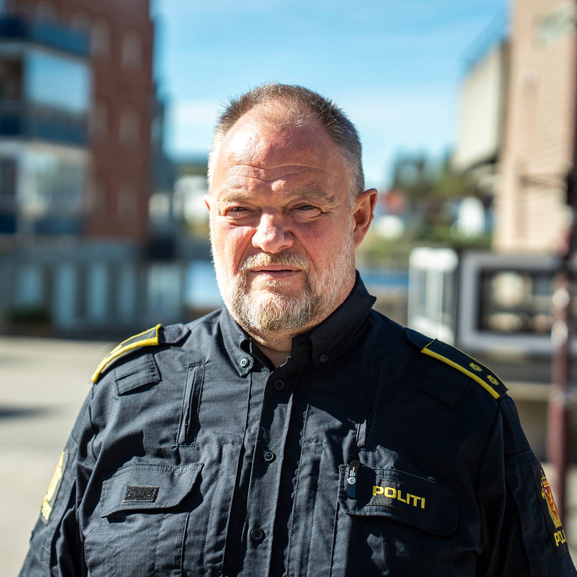 En eldre mann i politiuniform ser mot kamera. Han har grått skjegg og blondt, kort hår.