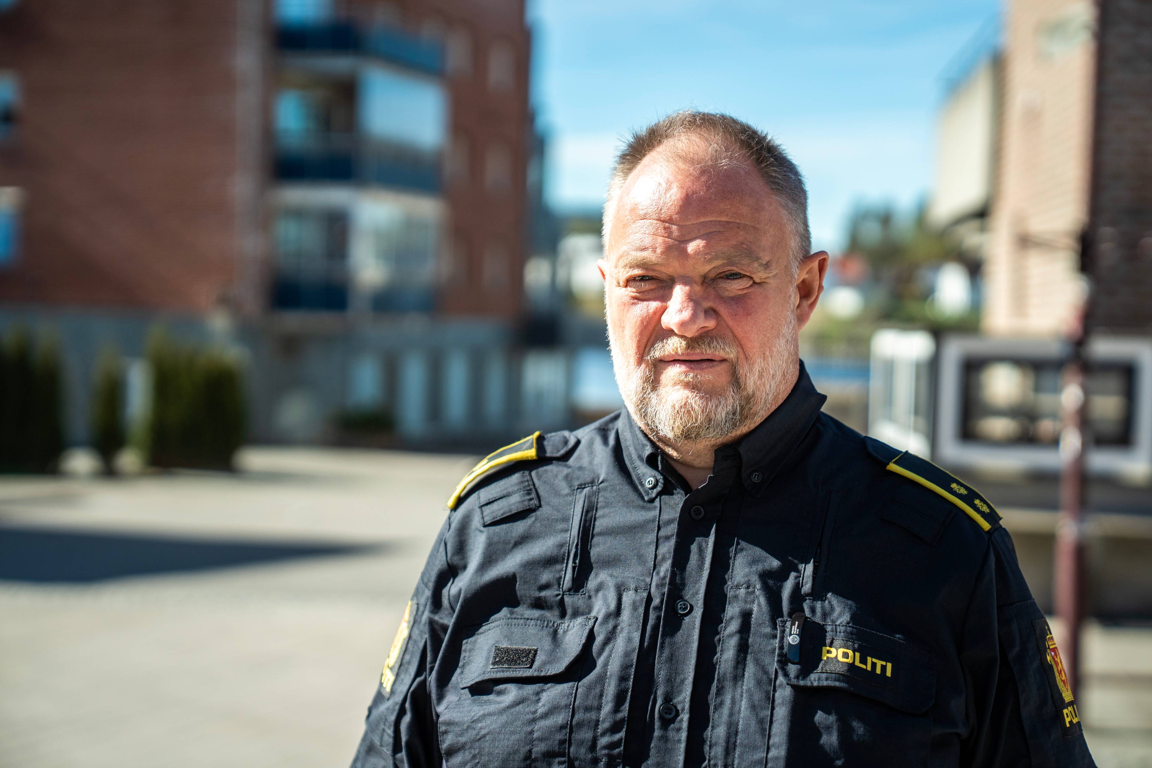 En eldre mann i politiuniform ser mot kamera. Han har grått skjegg og blondt, kort hår.