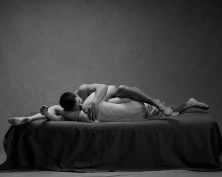 Et ungt par ligger på siden med hodet mot hverandres kjønnsorgan på en svart seng. Begge er nakne. Kvinnen har blondt hår og ligger med ryggen mot kamera. Mannen har mørkt hår og tatoveringer. De simulerer oral sex.