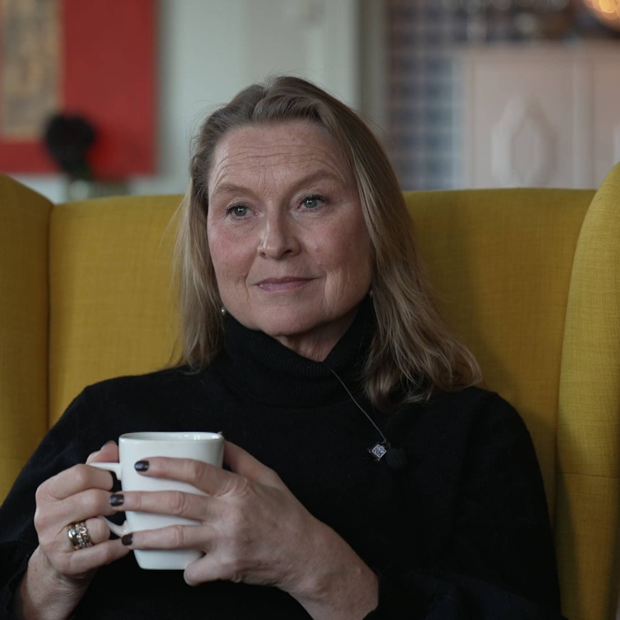 Kvinne med kaffekopp i gul stol