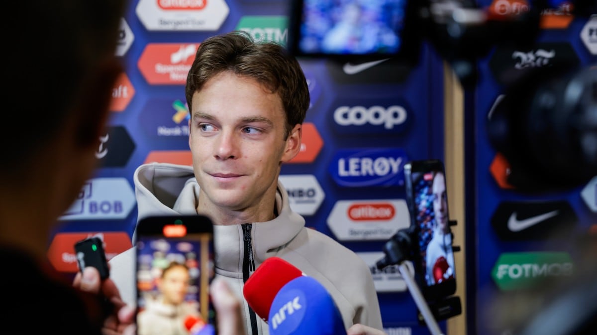 Mann intervjues av journalister med mikrofoner foran en bakgrunn med sponsorlogoer. (Bildebeskrivelsen er laget av en KI-tjeneste) FOTO: Paul S. Amundsen/NTB