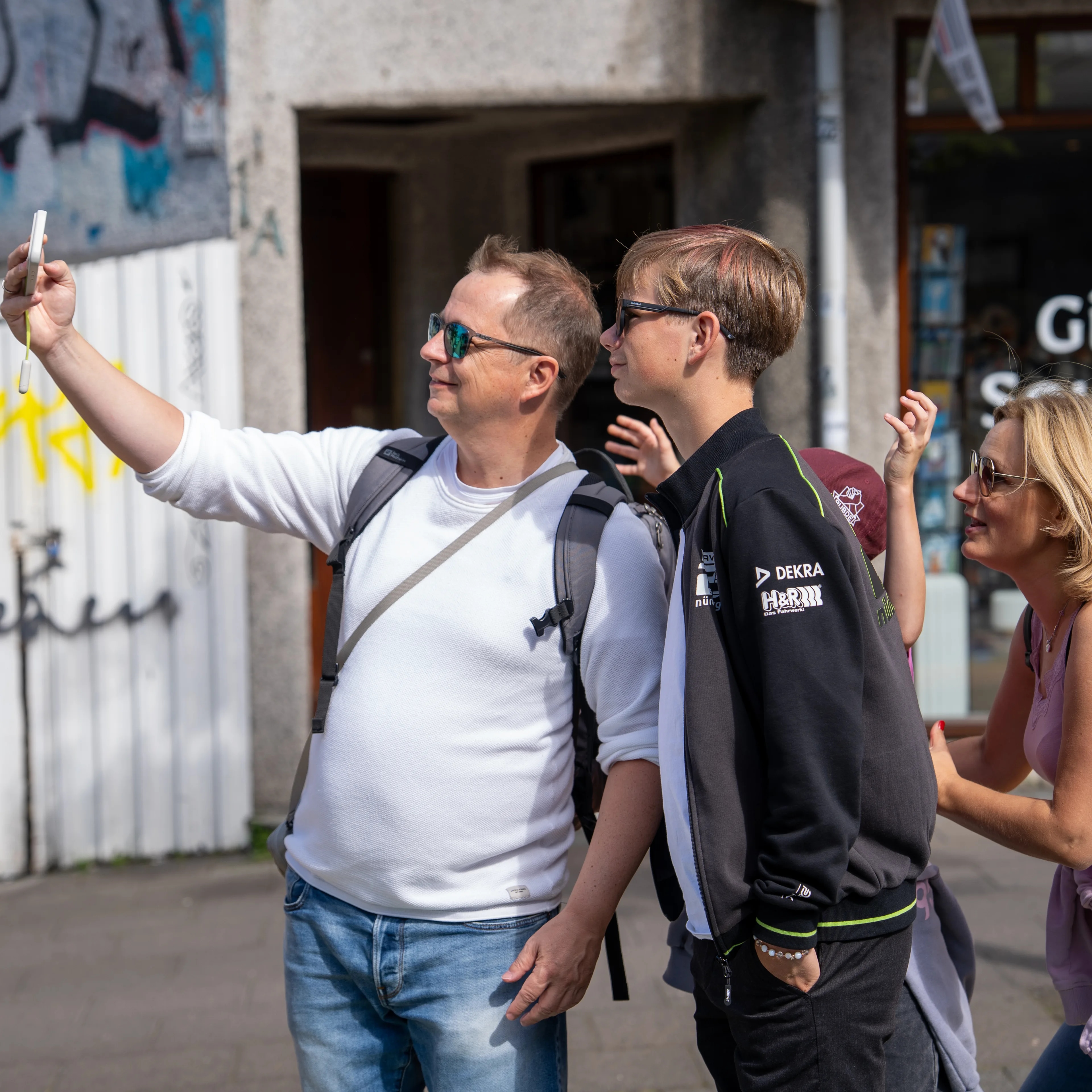 Tre personar tar ein selfie med mobiltelefonen i hovudgata i Reykjavk.